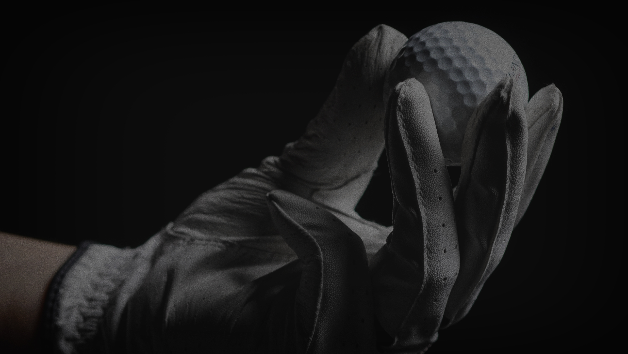 Golfer with golf glove holding white golf ball